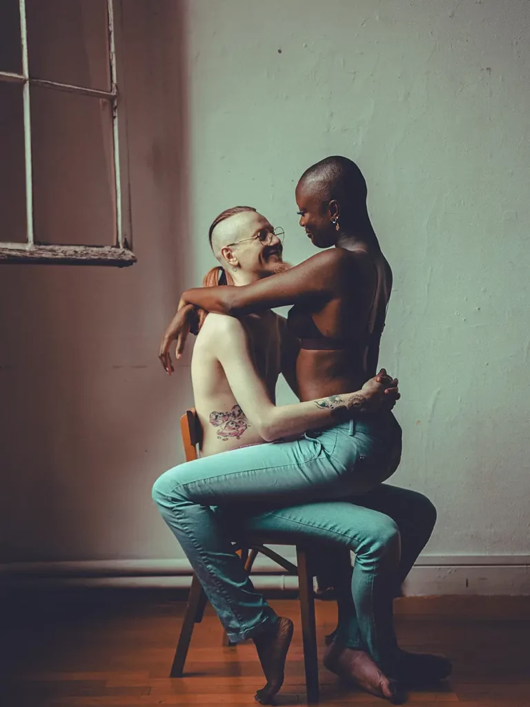 Un homme et une femme assis sur la même chaise. Il se regarde tendrement. Photo pour le magazine.