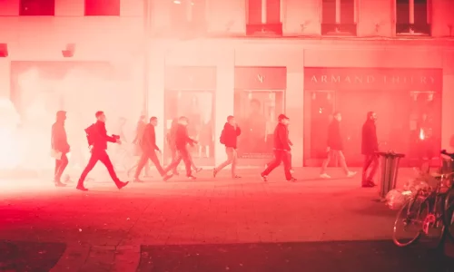 Une photo avec des fumigènes et un groupe de personne qui manifeste dans la rue.